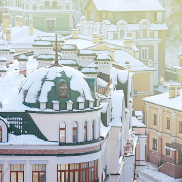 roofs of houses painted in different colors covered with snow and the sun