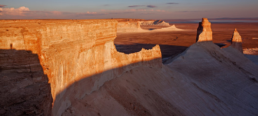 The Thumb Formation on Plateau Ustyurt in Kazakhstan on sunset with a figure of a person for scale.