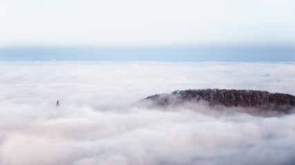 Hügel mit Bäumen versinkt im Wolkenmeer