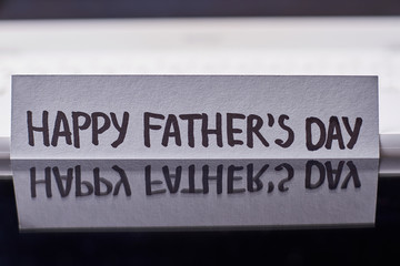 Reflection of Father's Day card. Greeting paper on black backdrop. Creative idea of congratulation.