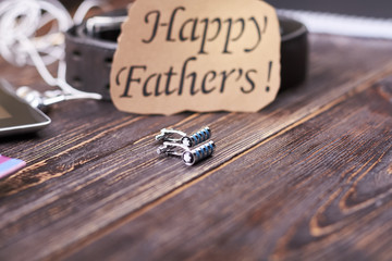 Cufflinks and Father's Day card. Belt near greeting paper. Prepare exclusive present for dad.