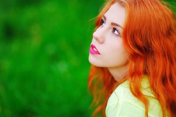 Naklejka premium portrait of a beautiful red-haired girl on grass