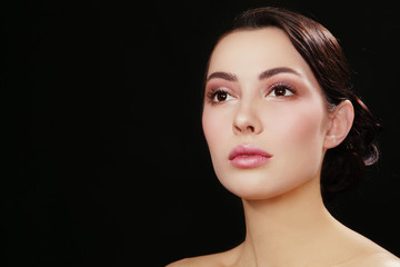 Fototapeta premium Portrait of young beautiful woman with fresh make-up looking upwards over dark background