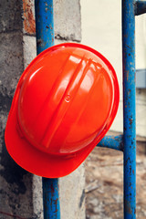 Orange helmet hung on blue scaffolding in construction site