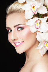 Close-up portrait of young beautiful healthy happy woman with fresh make-up and white orchid