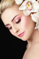 Fototapeta premium Close-up portrait of young beautiful healthy woman with fresh make-up and white orchid