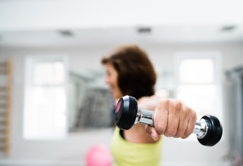 Senior woman in gym working out with weights.