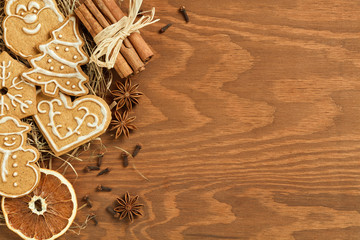 Christmas gingerbread on brown, wooden background with various decoration and spices