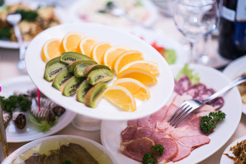 Fruit - kiwi, oranges. Against the background of the table with appetizers