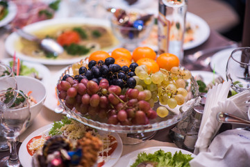 Fruits - Grapes, pears, tangerines. Against the background of the table with appetizers