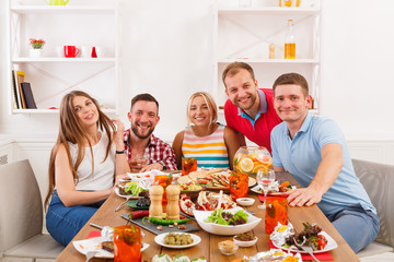 Group of happy young people at dinner table, friends party