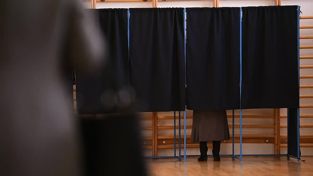 Unrecognizable people casting their votes inside voting booths during elections