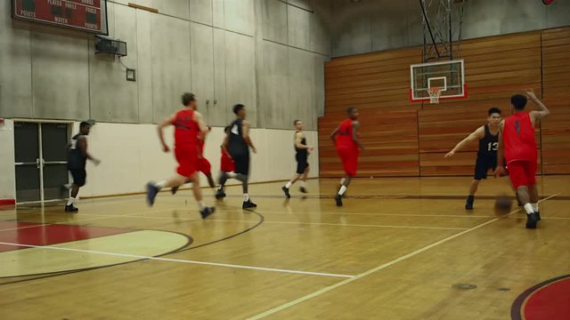 A basketball player stumbles and his opponent steals the ball and makes a basket