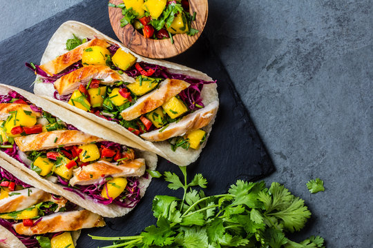Mexican chicken tacos with vegetables and mango. Slate background