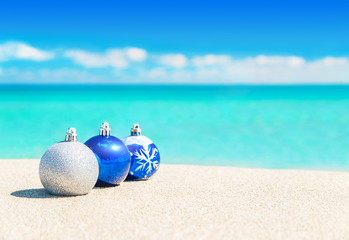 Christmas tree blue and silver balls decorations on beach sand
