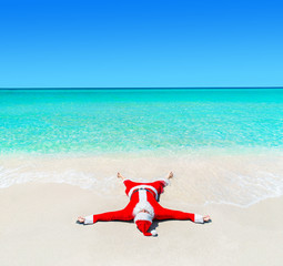 Christmas Santa Claus tanning at tropical ocean beach in waves