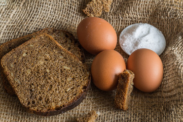 still life with black bread, eggs and salt on the burlap.