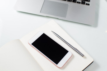 Desktop with laptop, mobile phone, note and stationery.