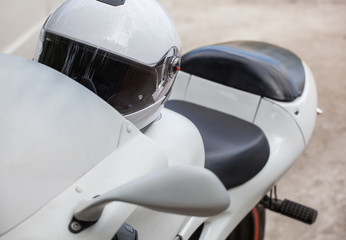 White sports motorcycle with a helmet parked on the roadside.