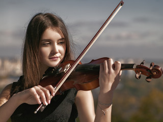 Young beauty musician playing his violin, urban female portrait