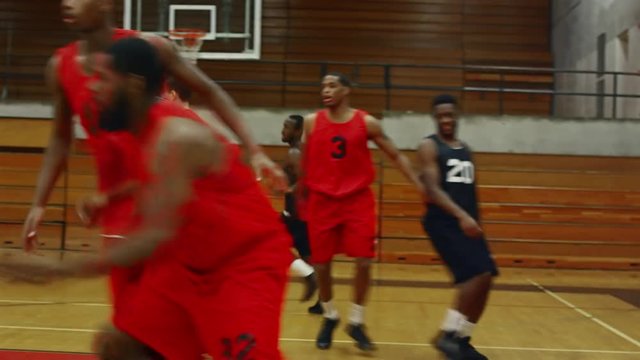 Following the action of basketball players on the court during a game, player makes a slam dunk