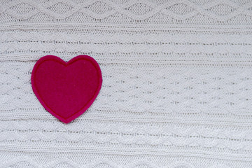 Red heart on white knitted background