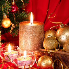 Burning candle, Christmas balls and fir tree. Red background
