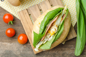 Homemade sandwich with ham, eggs, cheese and vegetables on white