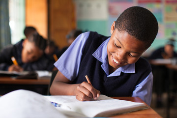 Young boy doing class work at a desk in a classroom in South Africa.