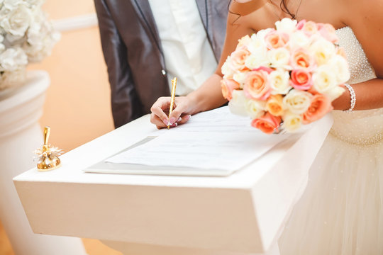 Bride And Groom Signing Marriage Wedding Certificate At Registry