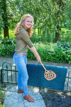 Young Dutch Woman Beating Door Mat With Carpet Beater