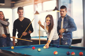 Group of young friends playing billiard