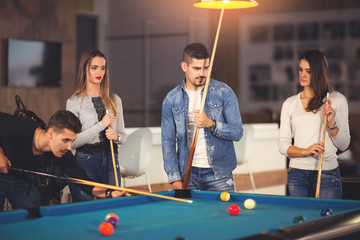 Fototapeta premium Group of young friends playing billiard