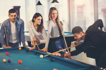 Fototapeta premium Group of young friends playing billiard