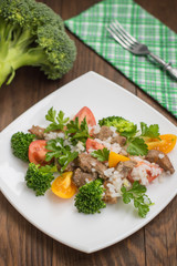 Roasted meat, white rice and vegetables. Wooden background. Top view. Close-up