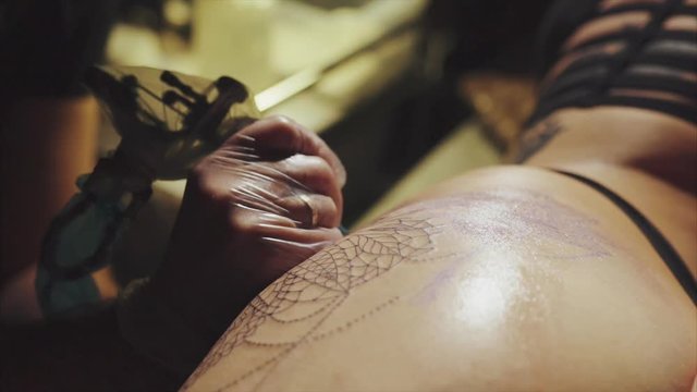 Close-up of hands of tattoo artist in gloves tattooing a pattern on body macro HD