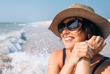 Fototapeta premium Happy smiling woman in straw hat on the sea beach