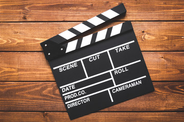 Screenwriter desktop with movie clapper board wooden background top view