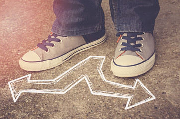 Sneakers on asphalt road with opposite arrows. Dilemmas concept.