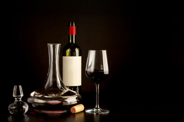 red wine bottle glass cork carefe on plain black background 