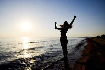 Fototapeta premium Silhouette of a girl against the sunset by the sea