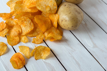 Fresh raw potatoes and chips with spice on a white wooden background
