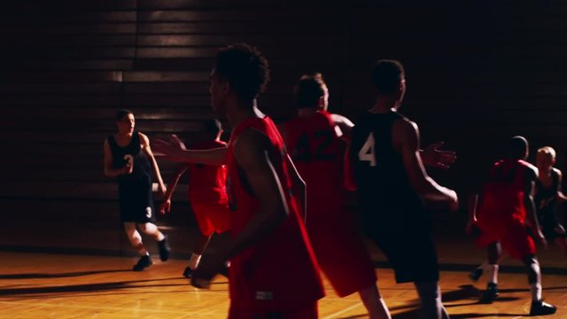 Basketball players passing the ball down the court during a game, slow motion