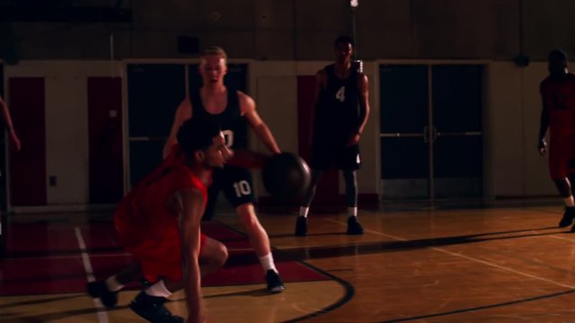 Basketball players passing the ball down the court during a game, slow motion