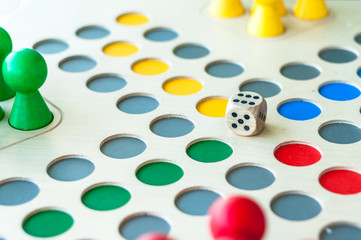 Wooden board game surface with colorful figurines and dice


