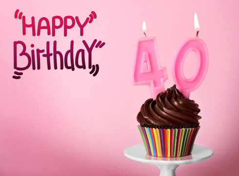 Cupcake with candles and text HAPPY BIRTHDAY on pink background