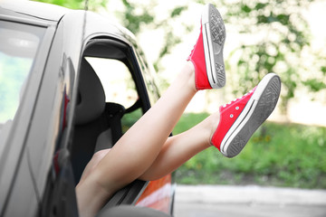 Female legs with red shoes through car window