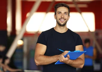 Foto op Aluminium Portrait of personal trainer holding clipboard with training plan in gym © Africa Studio