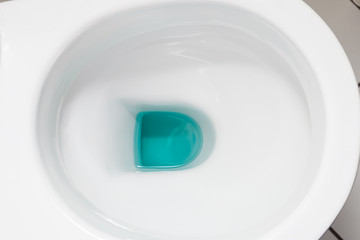 White toilet bowl with blue detergent