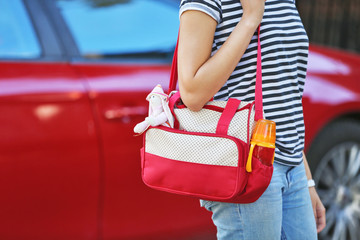 Woman with baby bag standing near a car